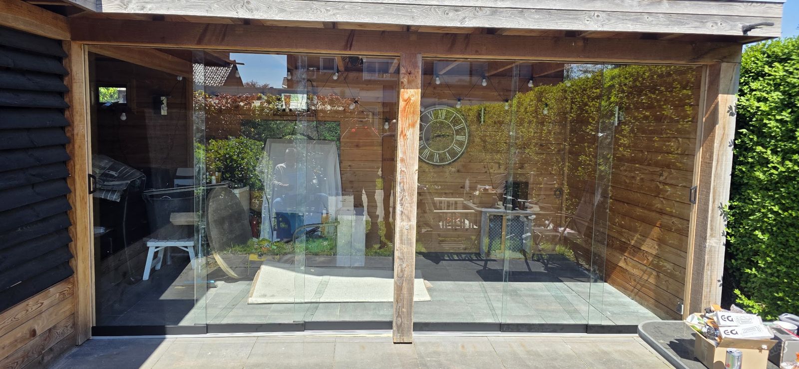 Glazen schuifwanden in een houten overkapping in een tuin